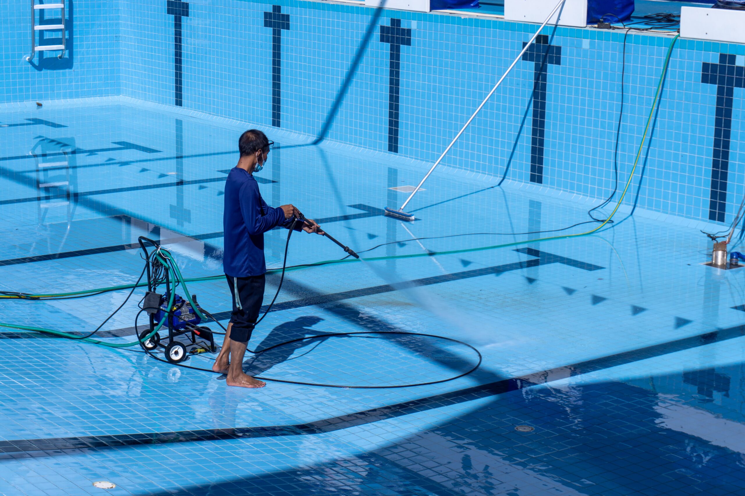 Swimming Pool Cleaning, A service man is cleaning the pool ground with a pressure pump