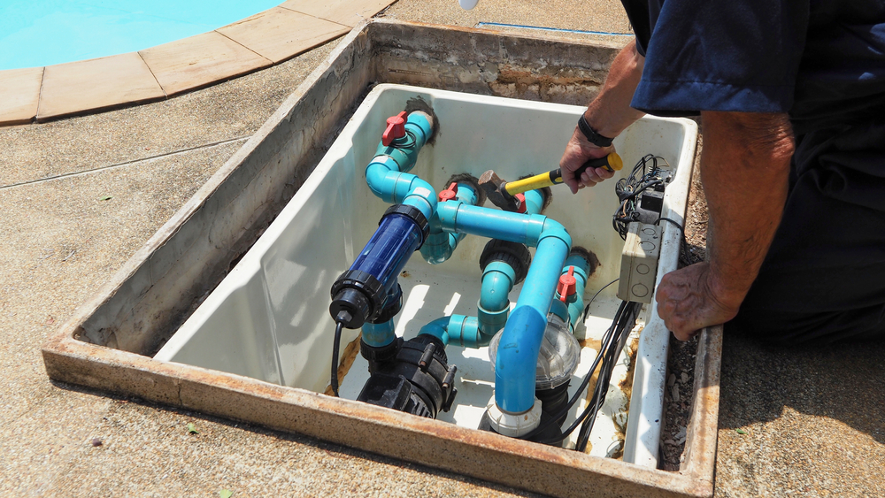 a person working on a pool pumps with a blue pipe
